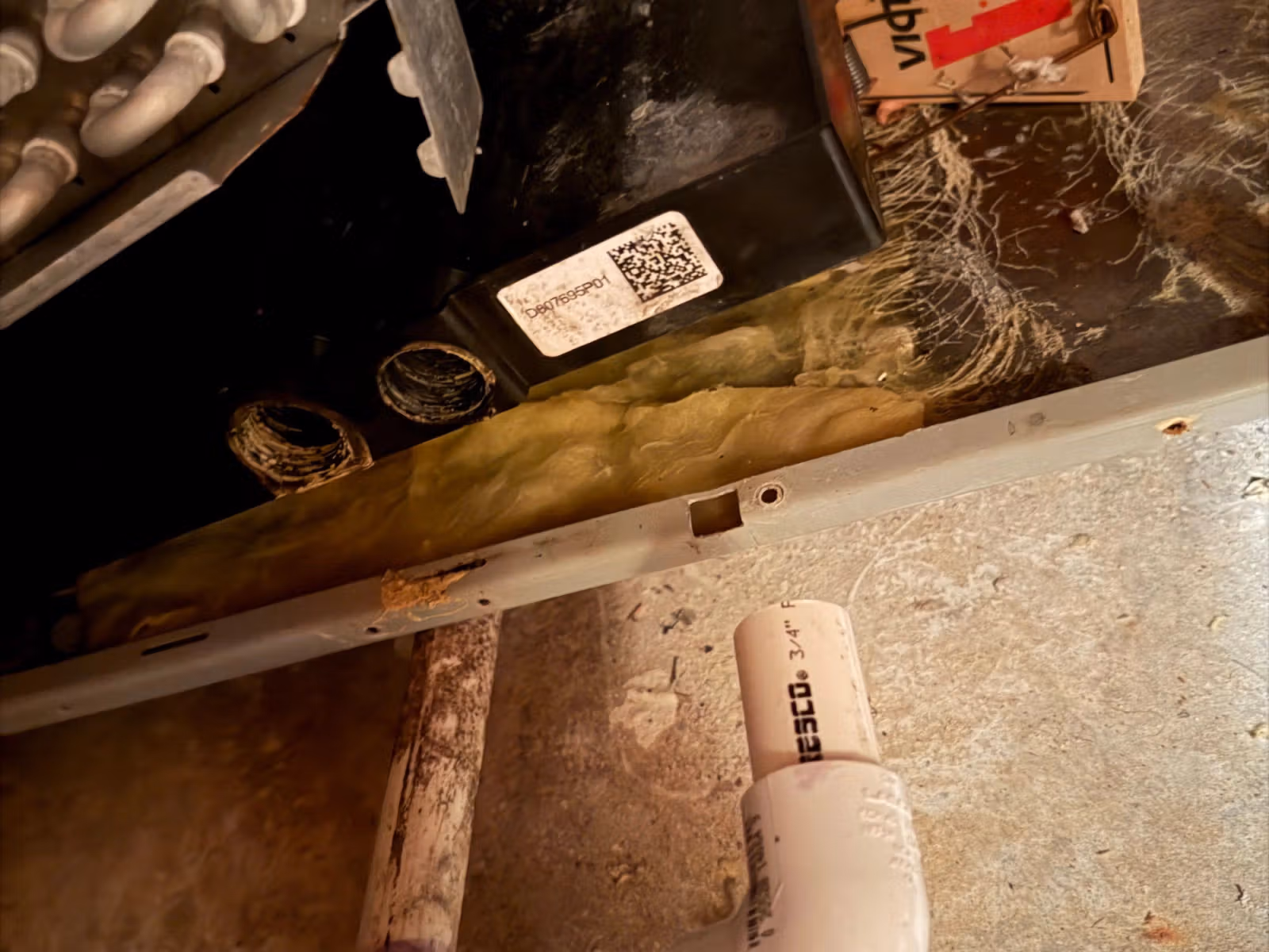 Interior of an HVAC unit showing dirty components, insulation, and disconnected drain piping