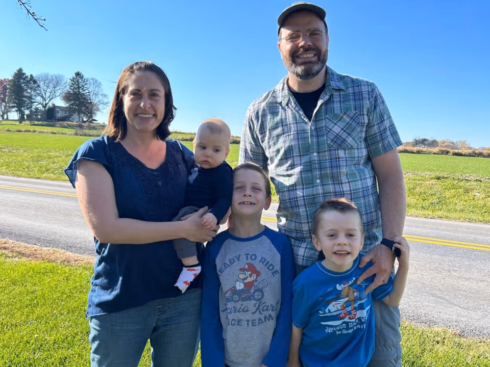 Shane with his wife and three sons standing outdoors near a rural road