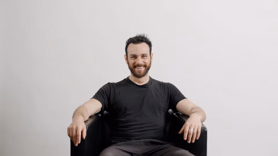 Zack seated in a chair wearing a black T-shirt and smiling at the camera.