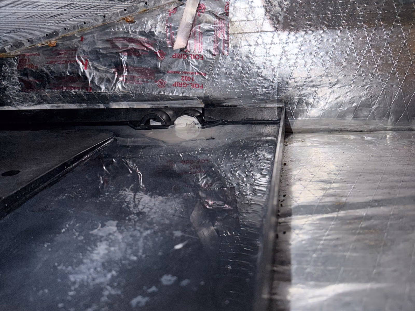 Close-up inside an HVAC unit showing foil sealing tape after repair work